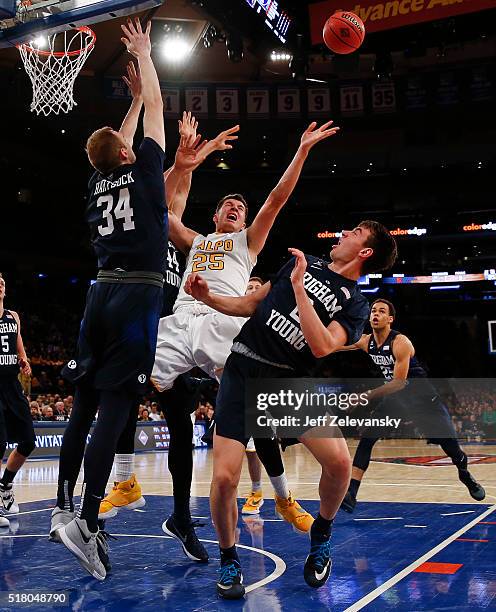 Alec Peters of the Valparaiso Crusaders is blocked by Jakob Heartsick and Zac Seljaas of the Brigham Young Cougars during their NIT Championship...