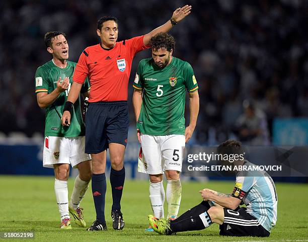 Venezuelan referee Jesus Valenzuela gestures next to Bolivia's Fernando Saucedo and Bolivia's Fernando Marteli as Argentina's Lionel Messi remains on...