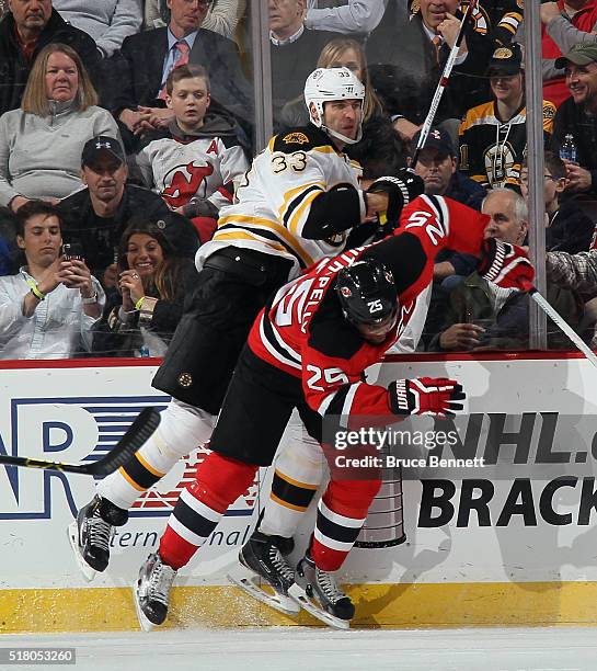 Devante Smith-Pelly of the New Jersey Devils checks Zdeno Chara of the Boston Bruins into the boards during the third period at the Prudential Center...