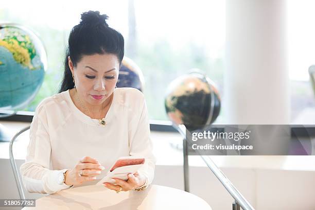 mature japanese woman using online services on smartphone - world social media day stock pictures, royalty-free photos & images