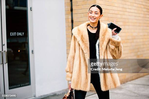 Korean/Serbian model Tiana Tolstoi throws a peace sign and wears a fur coat, a leather choker necklace with a ring, and gold eyeliner after the...