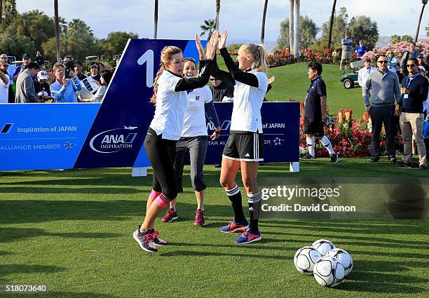 Paula Creamer of the United States is welcomed to the first tee by Abby Wambach of the United States soccer team during the ANA Footgolf Faceoff...