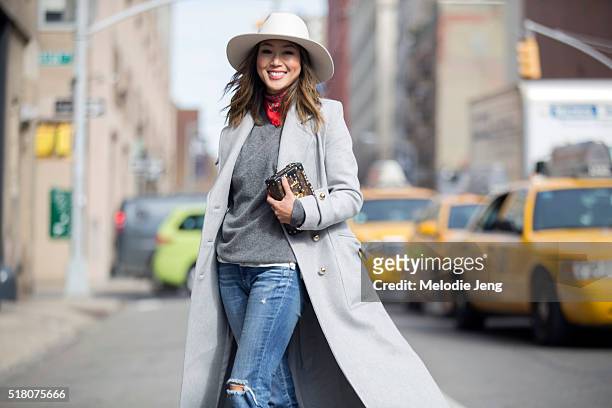 Blogger Aimee Song wears a gray Zimmermann coat, a white hat, red bandana around her neck, gray sweater, jeans, and a Louis Vuitton Petite Malle...