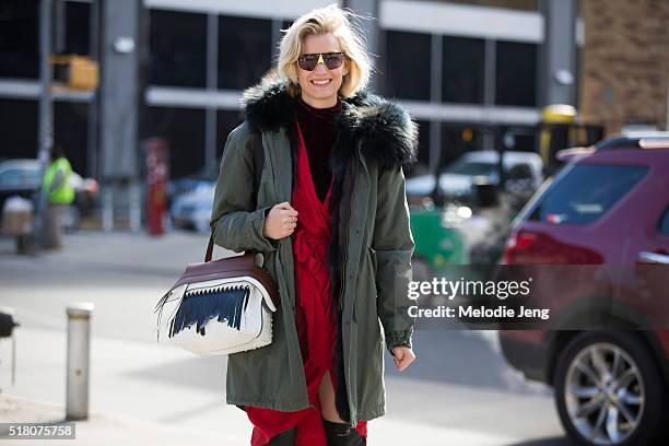 Zanita Whittington wears vintage sunglasses, a Mr & Mrs Italy green parka with a fur hood, a red Zimmermann robe-style dress, and a Tod's wave bag...