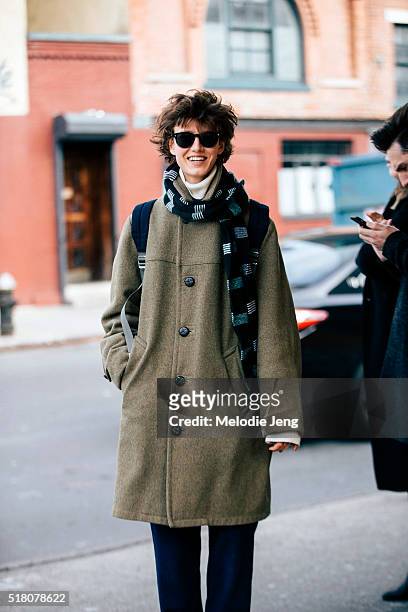 Russian model Alyosha Kovaleva exits the Suno show at Pier 59 in a blue scarf and an olive green coat with buttons. During New York Fashion Week:...