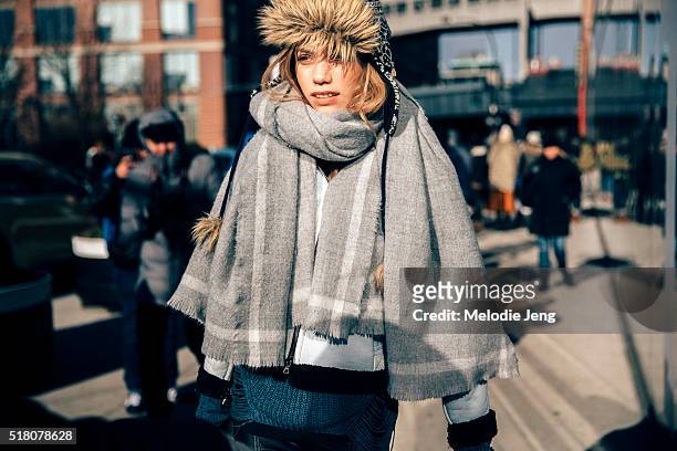 Model Laura Schellenberg exits the Tibi show at Skylight 60 Tenth in a fur cap and a wool/cashmere scarf with frayed edges during New York Fashion...