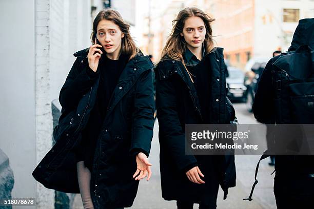 Russian twin models Lia Pavlova and Odette Pavlova exit the Lacoste show and talk on the phone at Spring Studios in black anoraks during New York...