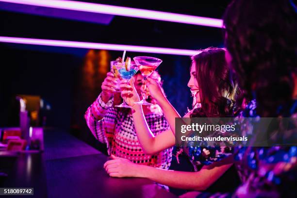 young girls toasting with drinks in a night club - girl swing stockfoto's en -beelden