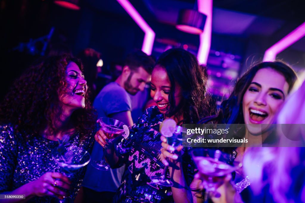 Happy young women enjoying cocktail in night club party
