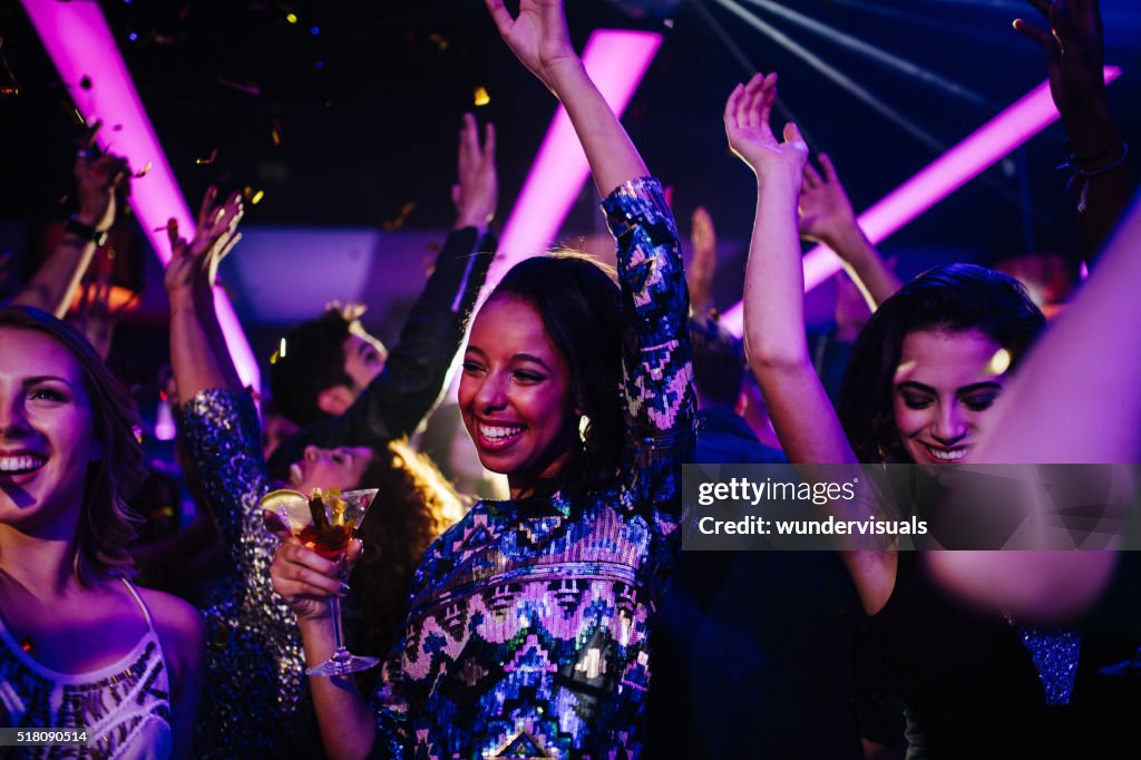 Happy young friends having funny party with confetti and cocktails