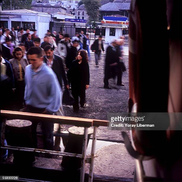Men and women get on a ferry boat before it leaves Uskundar station on the Asian side of Istanbul to Eminonu on the European side of the city in the...
