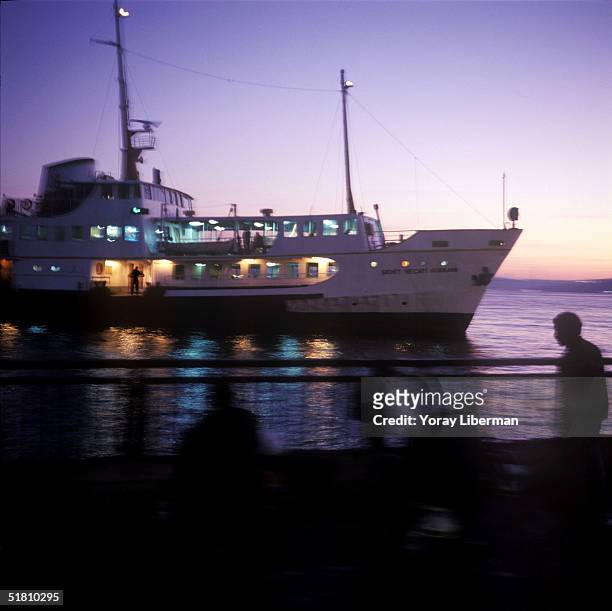 Ferry boat passes in front of fishermen on Eminonu ferry station's platform on the European side of Istanbul in the early morning of October 24, 2004...