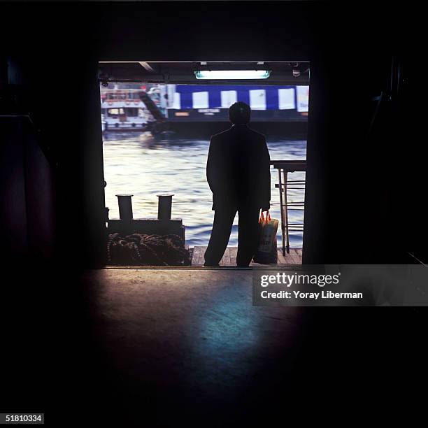 Turkish man stands on a ferry boat going from Eminonu on the European side of Istanbul to Kadikoy on the Asian side of the city in the early morning...