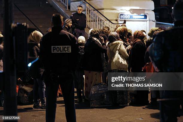 Migrants and refugees queue to get in a bus as they are evacuated by police officers and gendarmes from a makeshift camp under the Stalingrad railway...