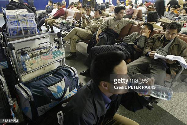 Passengers wait for delayed flights in the departure hall at Beijing International Airport, 02 December 2004. Large parts of China were shrouded in...