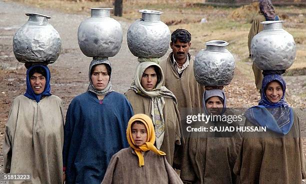 Indian Kashmiri girls carry water pots on their heads in the outskirts of Srinagar 02 December 2004. In rurar Kashmir, many people still go and...