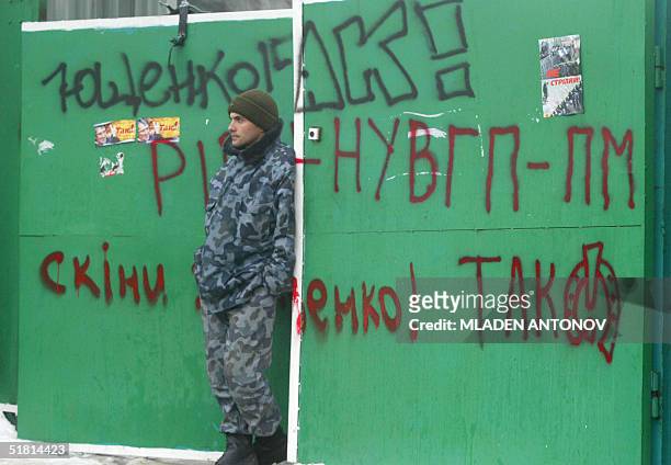 Man in uniform guards a gate covered with grafitti painted by supporters of Ukrainian opposition leader Viktor Yushchenko in central Kiev, 02...