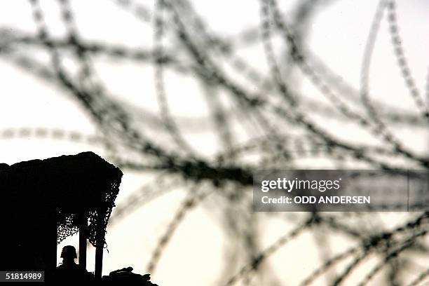 Marine standing in his watchtower is seen through barbed wire at the forward base St. Michael in the central Iraqi city of Mahmudiyah, 02 December...