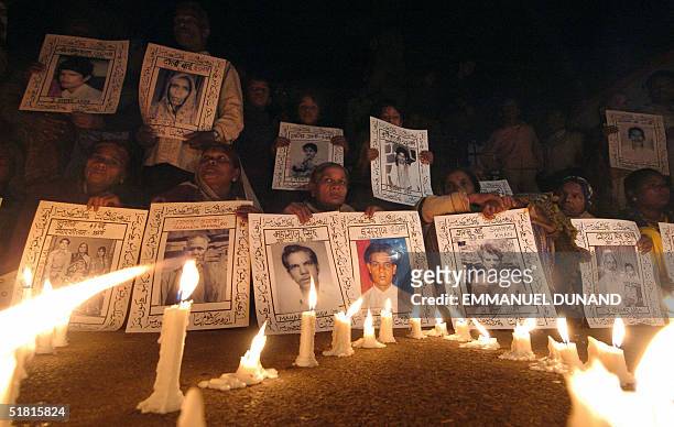 Bhopal gas leak victims and relatives, displaying portraits of lost loved ones, hold a candle light vigile to the victims to mark the 20th...