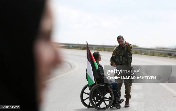 Palestinian protester on a wheelchair talks with an Israeli soldier during clashes with Israeli security forces following a demonstration to mark...