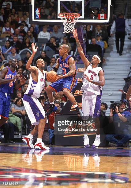 Anfernee Hardaway of the New York Knicks goes up for the basket between Loren Woods and Jalen Rose of the Toronto Raptors at Air Canada Centre on...