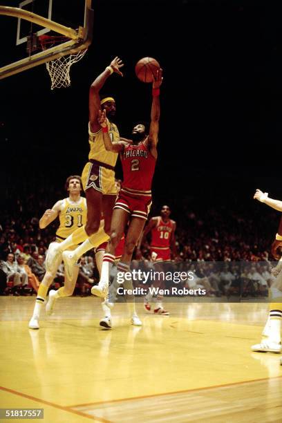 Norm Van Lier of the Chicago Bulls shoots a hookshot against Wilt Chamberlain of the Los Angeles Lakers during an NBA game circa 1973 at the Forum in...