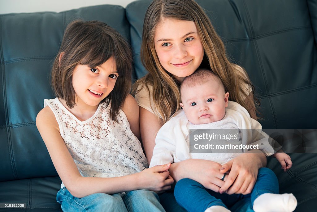 Retrato de três irmãs família sentada no sofá em casa.