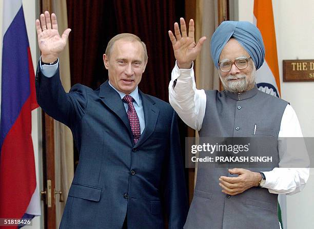 Visiting Russian President Vladimir Putin waves to the photographers along with Indian Prime Minister Manmohan Singh, 03 December 2004 in New Delhi...