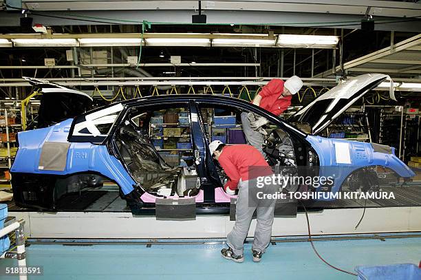 Workers assemble a Fuga laxury sedan at Nissan's Tochigi factory in Utsunomiya city, about 100 kilometres north of Tokyo, 03 December 2004....