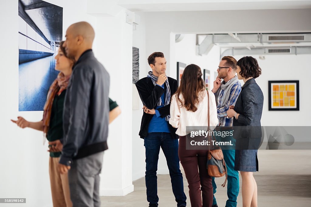 I visitatori In una galleria d'arte che guarda arte e parlando
