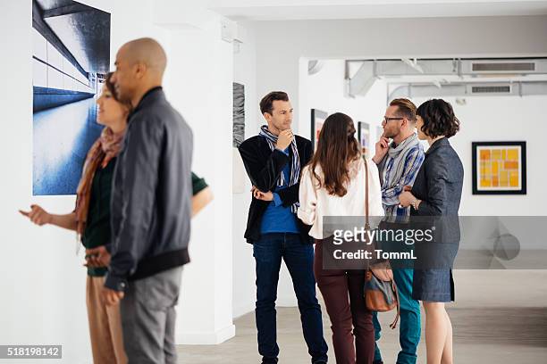 i visitatori in una galleria d'arte che guarda arte e parlando - exhibition foto e immagini stock