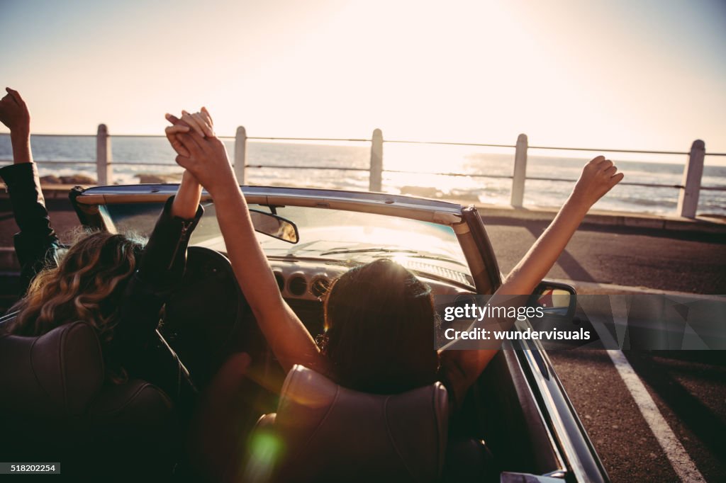 Glückliche Mädchen Freunde Jubeln mit erhöhter Arme in einem Cabrio