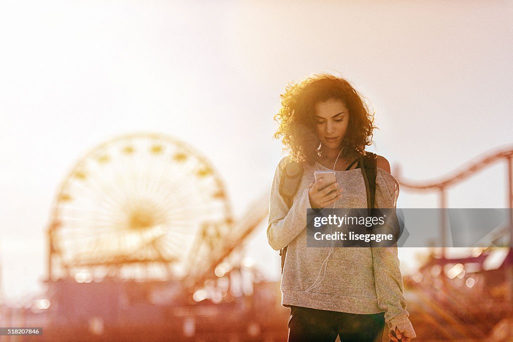 Woman exercising in LA, using smartphone, California