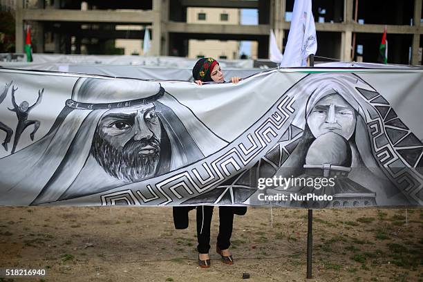 Woman look past large banners made by Palestinian artists marking the 40th Land Day anniversary, in Gaza City, Wednesday, March 30, 2016. Land Day...