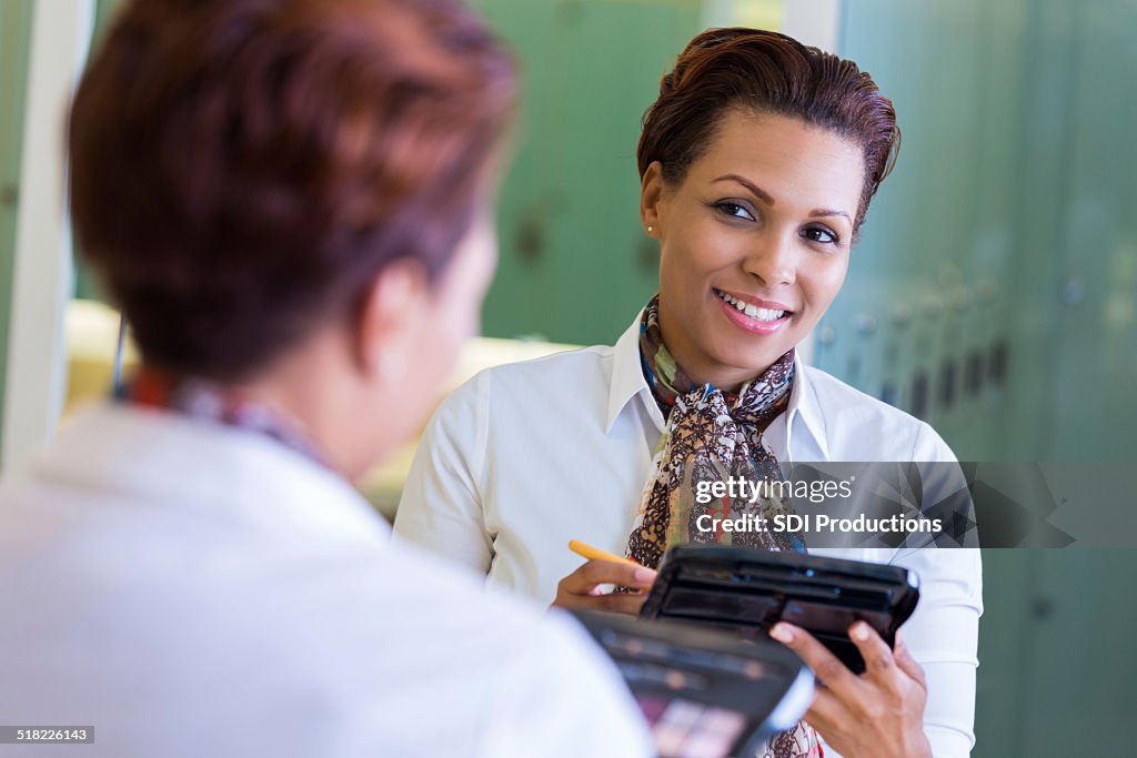 Professional woman applying makeup in gym locker room