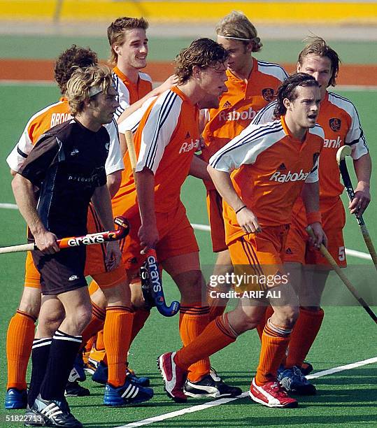 Dutch field hockey players celebrate a goal as New Zealand's team captain Simon Towns looks on during the opening match of the six-nation Champions...