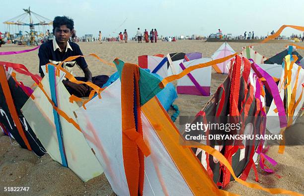 Indian 15-year-old kite seller K. Kumareshan waits for customers beside his kites on display at the Marina beach in Madras 04 December 2004....