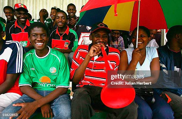 Members of the crowd shelter from the rain during the 3rd One Day International played at The Queens Sports Club in Bulawayo on December 4, 2004 in...