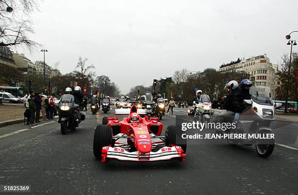 Seven-time world champion Germany's Michael Schumacher drives his Ferrari, 05 December 2004, in the streets of Paris, to support a new brain and...