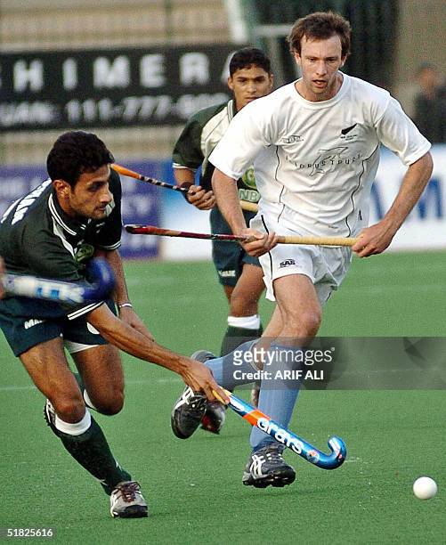 Pakistani field hockey player Ghazenfar Ali is tackled by New Zealand player Dean Couzins during the six-nation Champions Trophey field hockey...