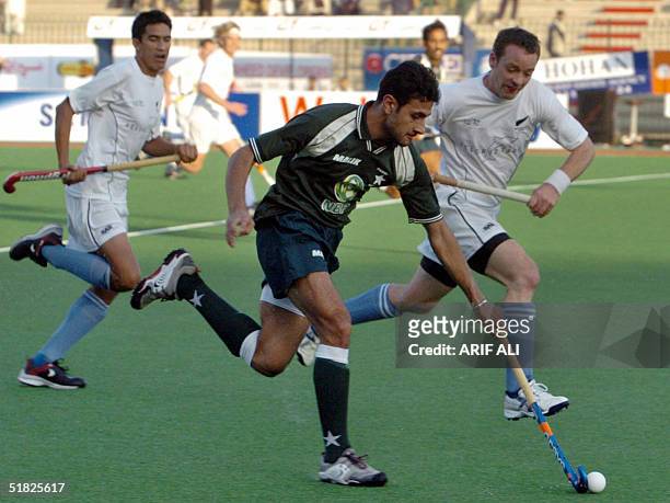 Pakistani field hockey player Ghazenfar Ali is tackled by New Zealand player Dion Gosling during the six-nation Champions Trophy field hockey...
