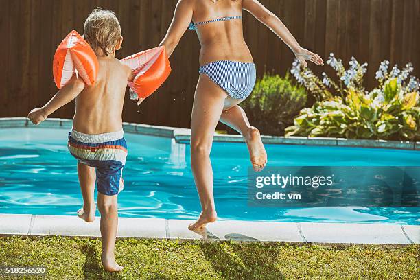 brother and sister running and jumping into a pool - young girl jumping into swimming pool stock pictures, royalty-free photos & images