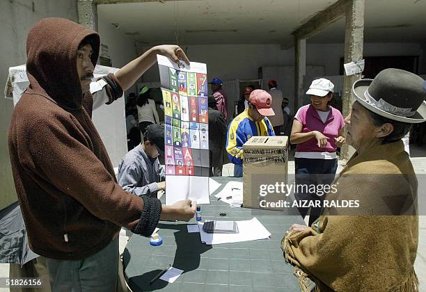 Un jurado electoral le muestra la papeleta de sufragio a una mujer de la etnia aymara antes de emitir su voto el 05 de diciembre de 2004 en la Paz,...