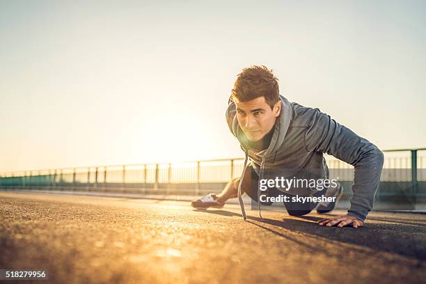 athletic man doing push-up on a road at sunset. - opdrukken stockfoto's en -beelden