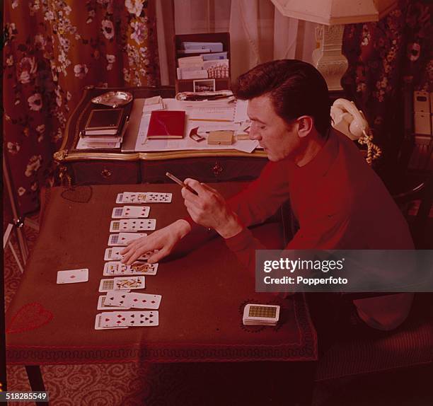 Actor Laurence Harvey plays a patience or solitaire card game at home in 1965.