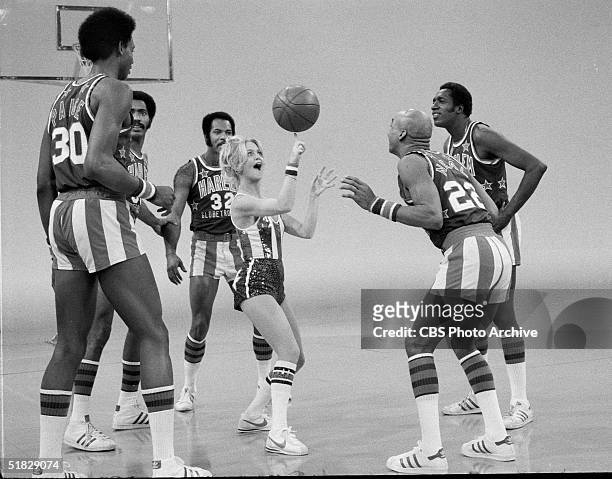 American actress Goldie Hawn spins a basketball on her finger while performing with the Harlem Globetrotters, including Robert Paige , Curley Neal ,...