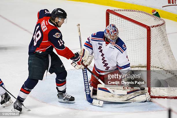 Goaltender Dawson Carty of the Kitchener Rangers makes a glove save against forward Christian Fischer of the Windsor Spitfires during game 4 of the...