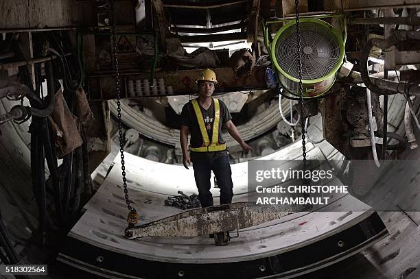 This picture taken on March 11, 2016 shows a worker standing on curved concrete segments to be attached to form the inner surface of a tunnel being...