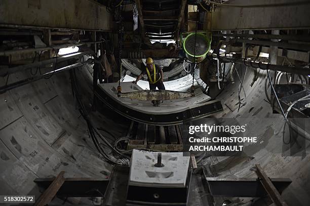 This picture taken on March 11, 2016 shows workers preparing curved concrete segments to be attached to form the inner surface of a tunnel being dug...