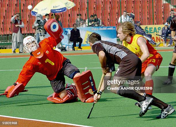 Spainish field hockey goalkeeper Herrera Barnardino stops a shot by New Zealand's Blair Hopping during the six-nation Champions Trophy tournament...